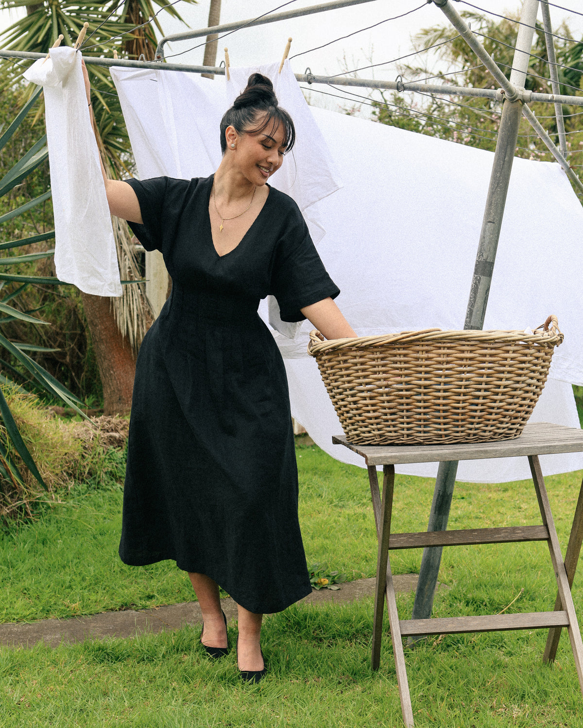 Winnie black linen maxi dress – full length front, holding a washing basket